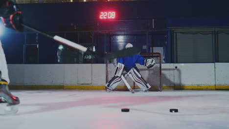 Close-up-of-a-hockey-puck-in-slow-motion-and-a-putter-of-several-pucks-in-turn-and-a-goalkeeper-in-the-background